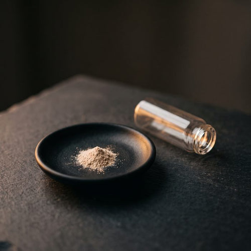 Kleine Menge Pulver auf einem schwarzen Schälchen neben einer Glasampulle